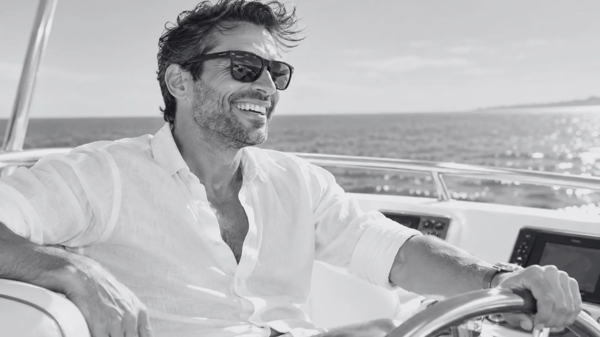 Happy man in his 40s enjoying the sunlight while steering a luxury yacht on the open sea.
